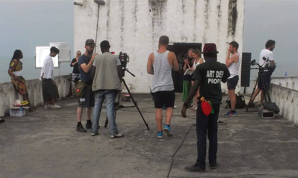 Prince Kojo-Hilton on a film set at a coastal fort in Ghana with the art department and camera crew