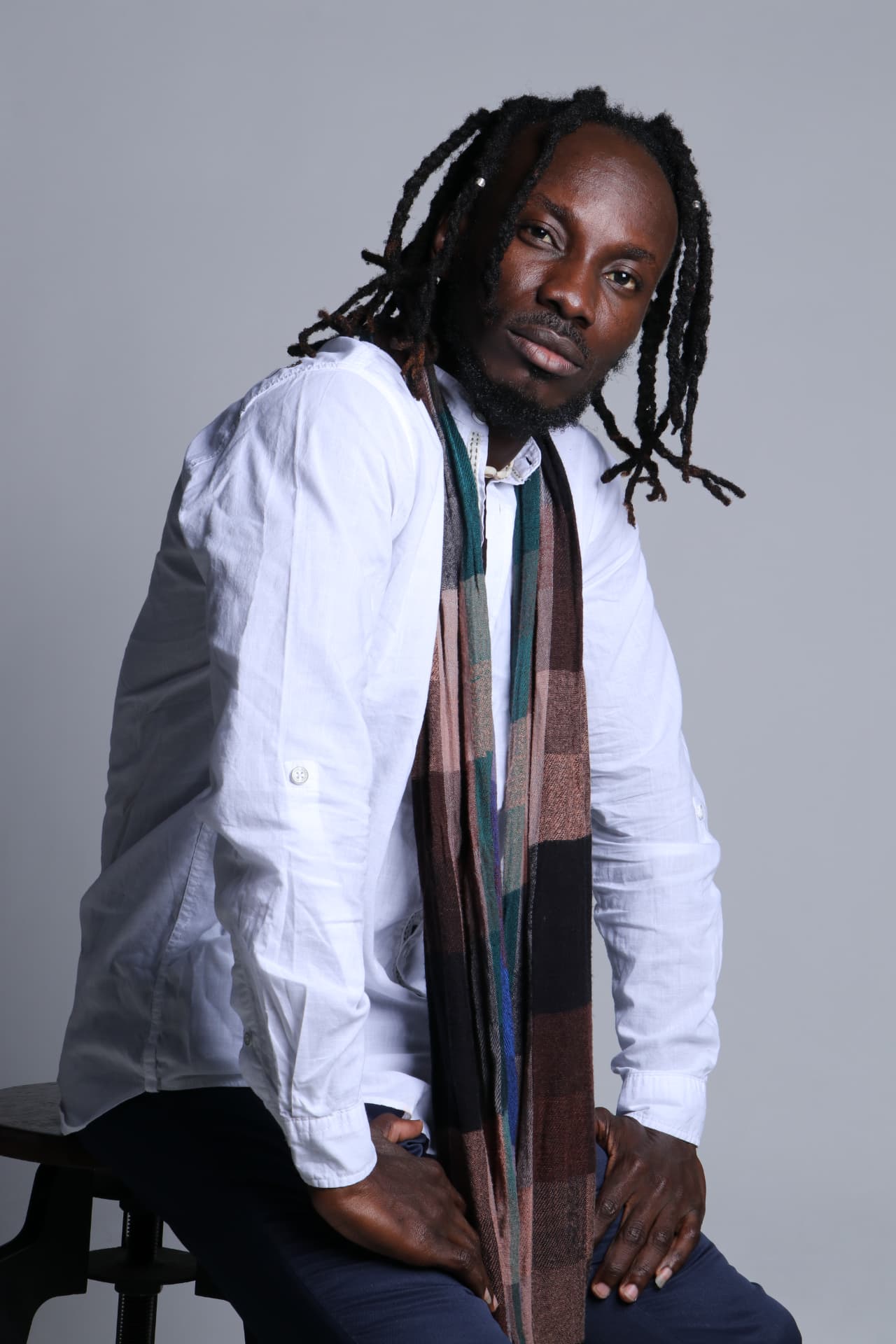 Trevor Georges seated in a white shirt with a woven scarf