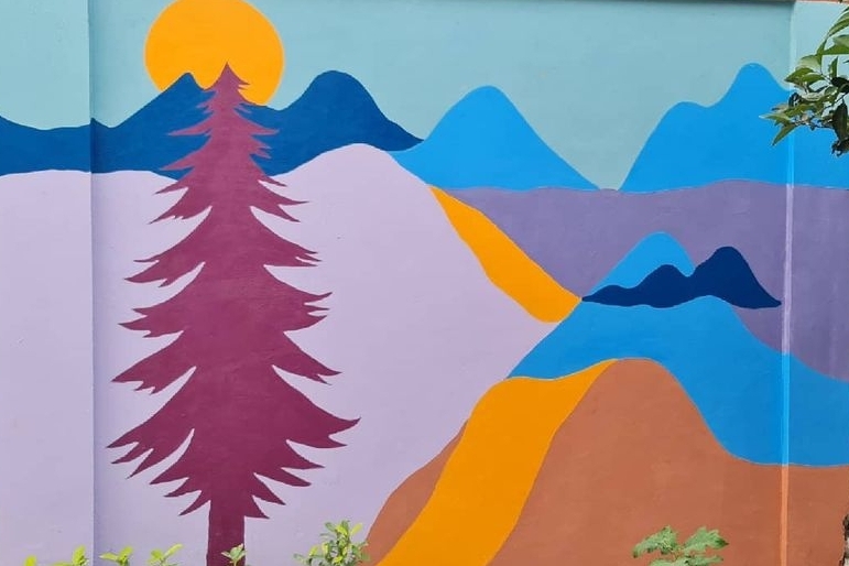 Mural of mountains, sun and pine tree painted by Kizito Nii Amarh Amartey